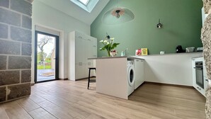 A modern kitchen with a built-in washing machine, a dining area with a table and chairs, and a large window providing natural light.