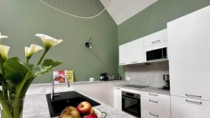A modern kitchen with white cabinets, a sink, and a colander with apples.