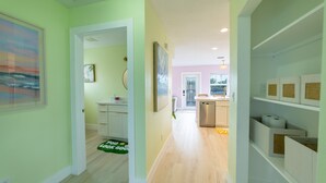 A hallway with a kitchen area, a dining area, and a bathroom visible in the background. - Tropical Treetop Hideaway Just a Short Walk to Beach (Lake Worth Beach)