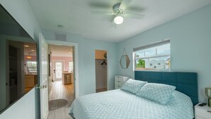 A bedroom with a bed, a ceiling fan, a window, and a door leading to a bathroom. - Tropical Treetop Hideaway Just a Short Walk to Beach (Lake Worth Beach)