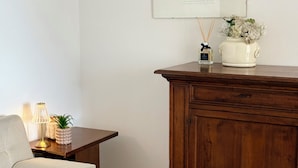 A room with a wooden cabinet, a framed picture on the wall, a small table with a lamp, and a sofa. - Spacious 95 sqm newly renovated vacation home with breathtaking views (Menaggio)