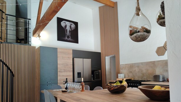 A modern kitchen with a wooden island, a hanging light fixture, and a framed elephant picture on the wall.
