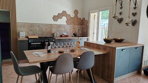 A modern kitchen with a wooden island, dining chairs, and a view of the outdoors.