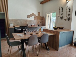 A modern kitchen with a wooden island, dining chairs, and a view of the outdoors.
