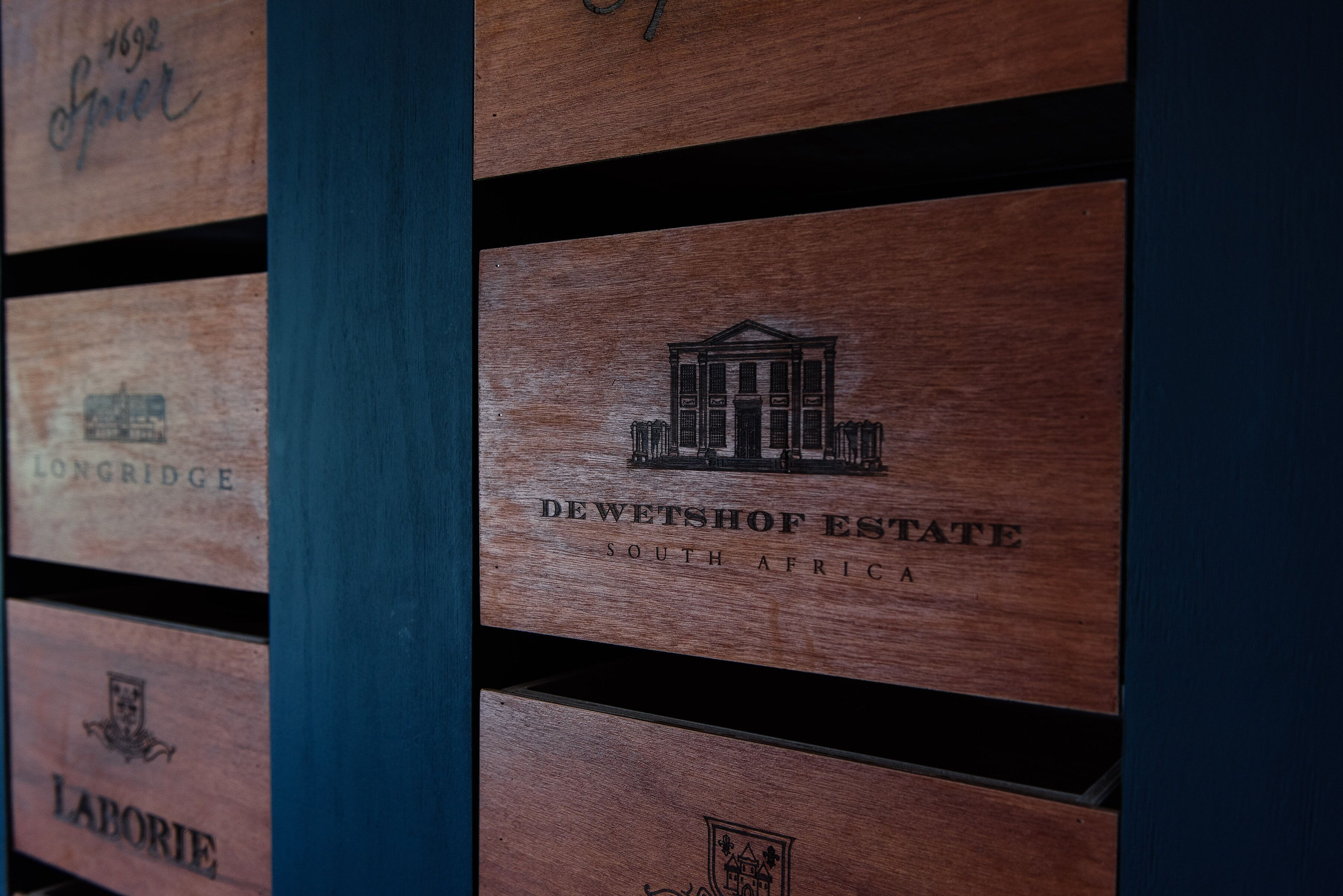 Wooden panels with embossed logos and names, including "DEWETSHOF ESTATE SOUTH AFRICA".