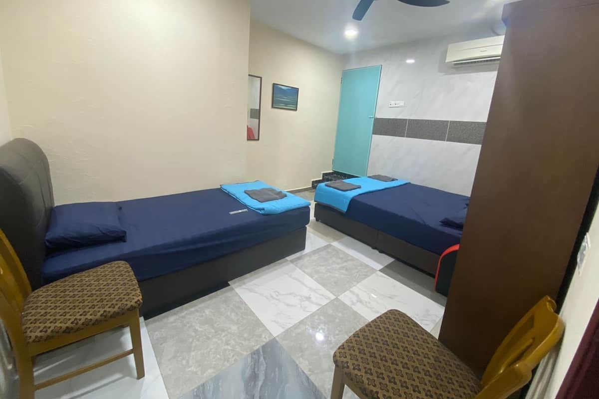 A room with two single beds, a ceiling fan, a small table, and two chairs.