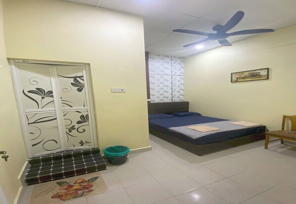 A bedroom with a bed, a ceiling fan, a window with patterned curtains, and a door with decorative panels. - Hotel O Ray Yan Guesthouse (George Town)
