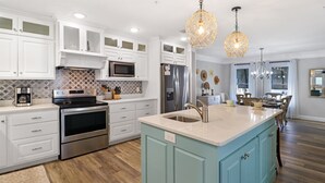 A modern kitchen with white cabinets, stainless steel appliances, a blue island, and pendant lighting. - Huge renovated townhome, sleeps 11, beach-side of 98 with gorgeous beach access (Me)