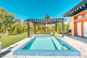 A swimming pool with a tiled edge, a pergola, and a patio area with outdoor furniture. - Tranquil Bungalow w Pool at Green Village Ca (Punta Cana)
