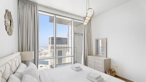 Een moderne hotelkamer met een groot bed, uitzicht op de stad, een dressoir en een spiegel.