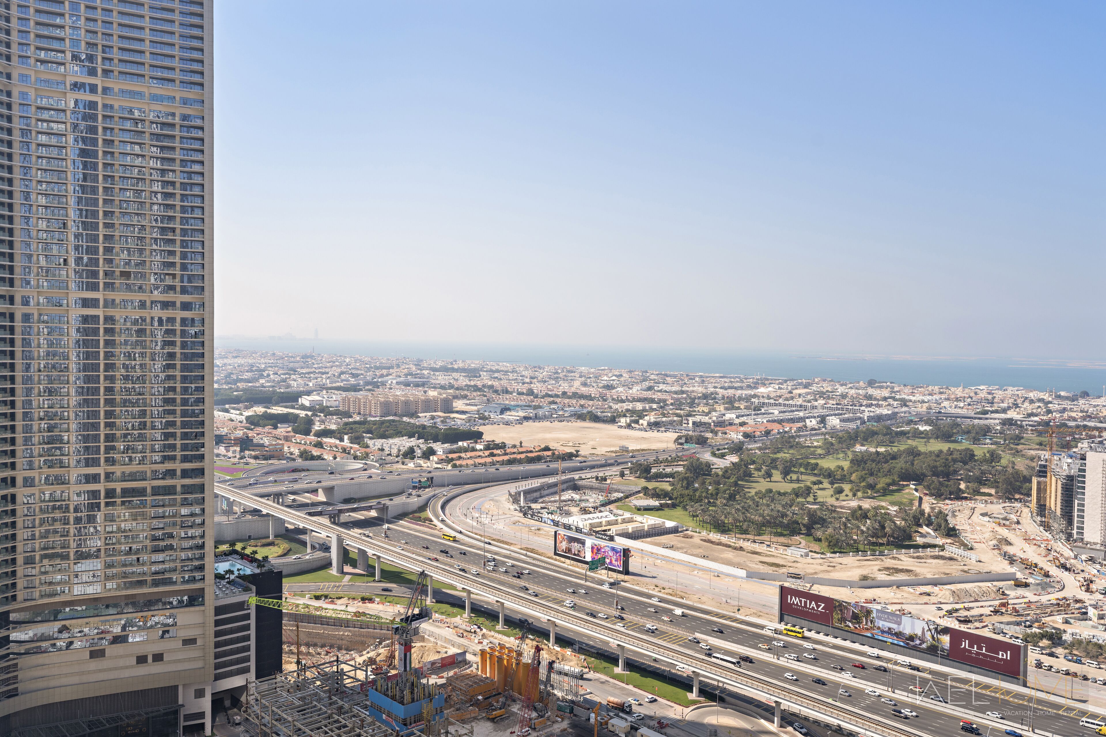 A high-rise building with a view of a cityscape, including roads and construction sites.