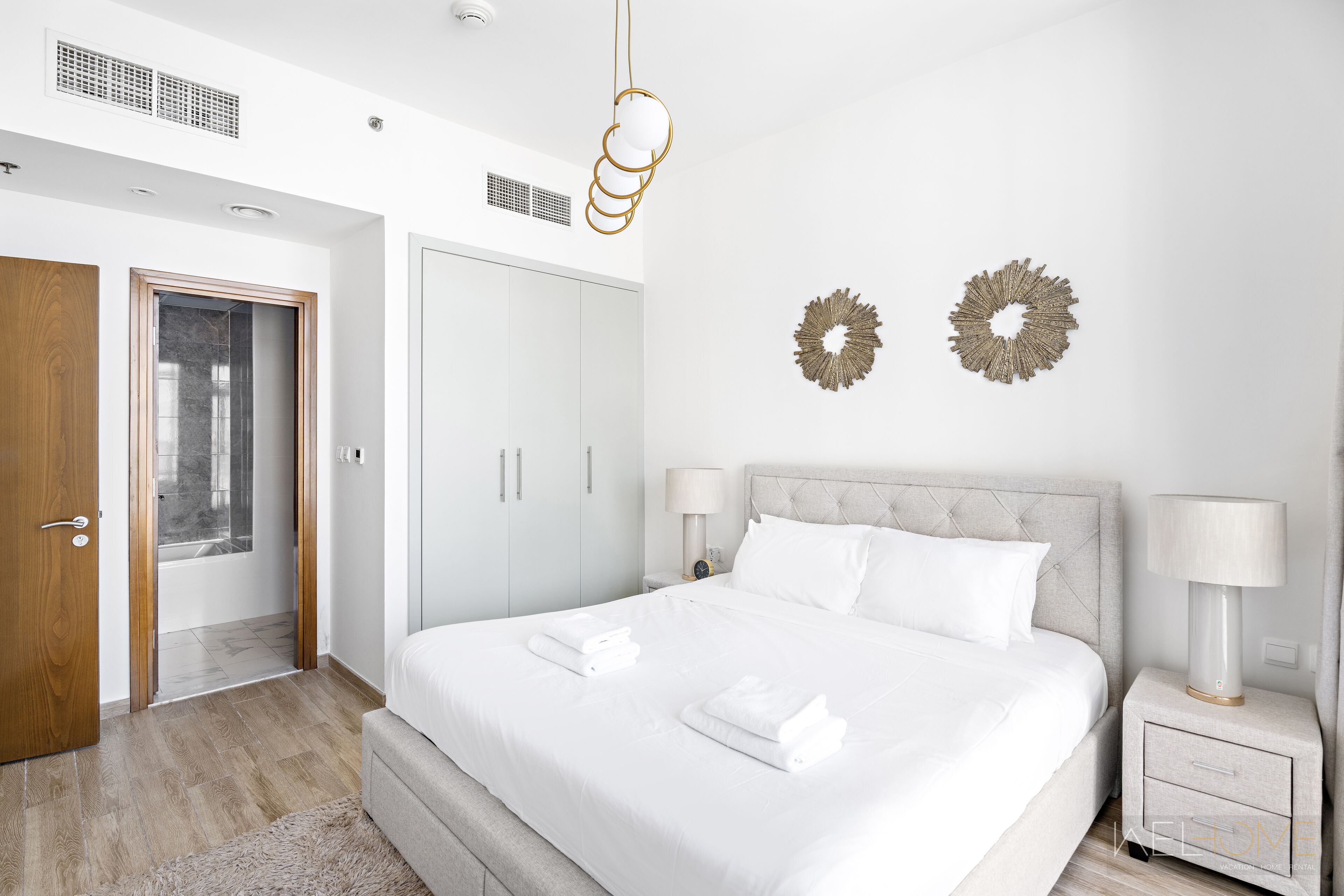 Un dormitorio moderno con una cama grande, dos mesitas de noche, un armario y decoración en la pared.