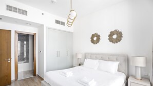 Een moderne slaapkamer met een groot bed, twee nachtkastjes, een kledingkast en decoratieve wandkunst.