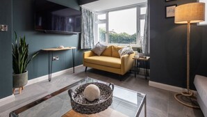 A modern living room with a sofa, a coffee table, a TV, and a window with curtains.