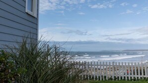 A coastal view with a white picket fence, ocean waves, and a clear sky. - 2 Bed Beach House in a fantastic sea front setting (Westward Ho!)