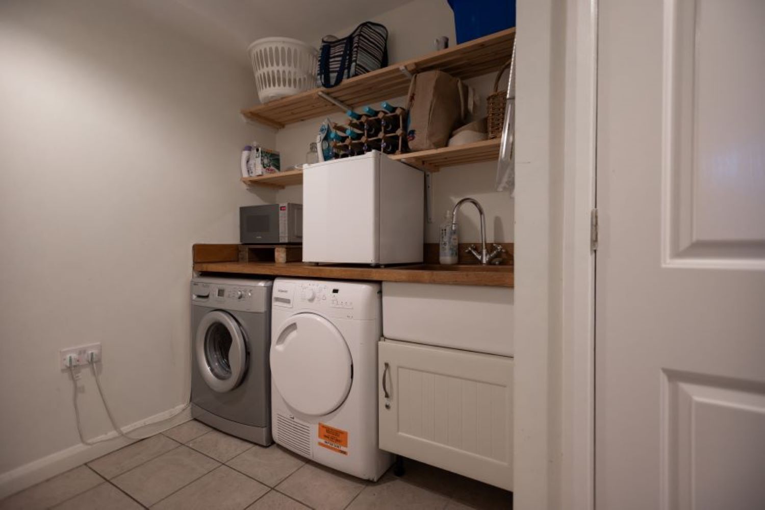 A laundry room with two washing machines, a dryer, and a sink.