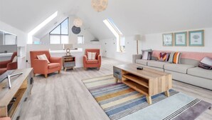 Un appartement-loft spacieux avec de hauts plafonds, de grandes fenêtres, un ensemble de canapés modernes et une table basse en bois.
