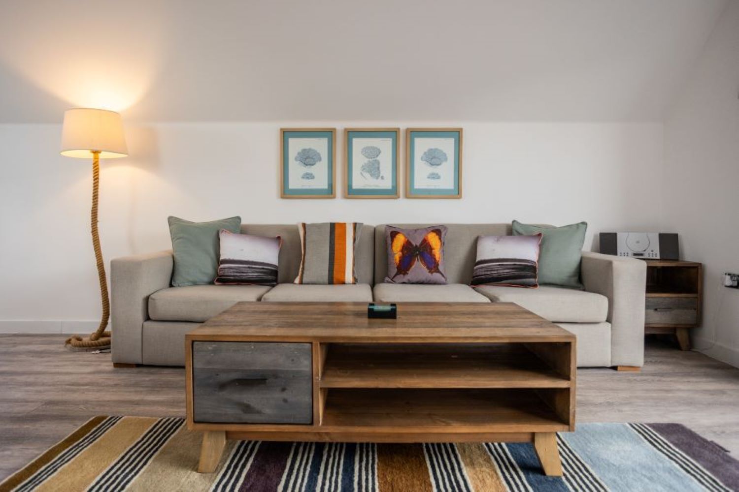 A living room with a sofa, a coffee table, a lamp, and framed artwork on the wall.