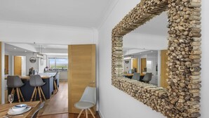 A modern kitchen with a central island, wooden flooring, and a large mirror with a stone frame. - Luxury 4 bed beachside home with coastal views (Westward Ho!)
