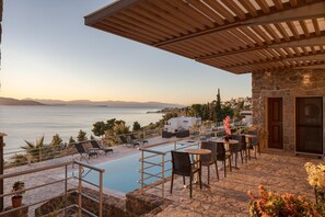 Ein Poolbereich mit Liegestühlen, einem kleinen Pool und einem Steinhaus mit einer Holzpergola.