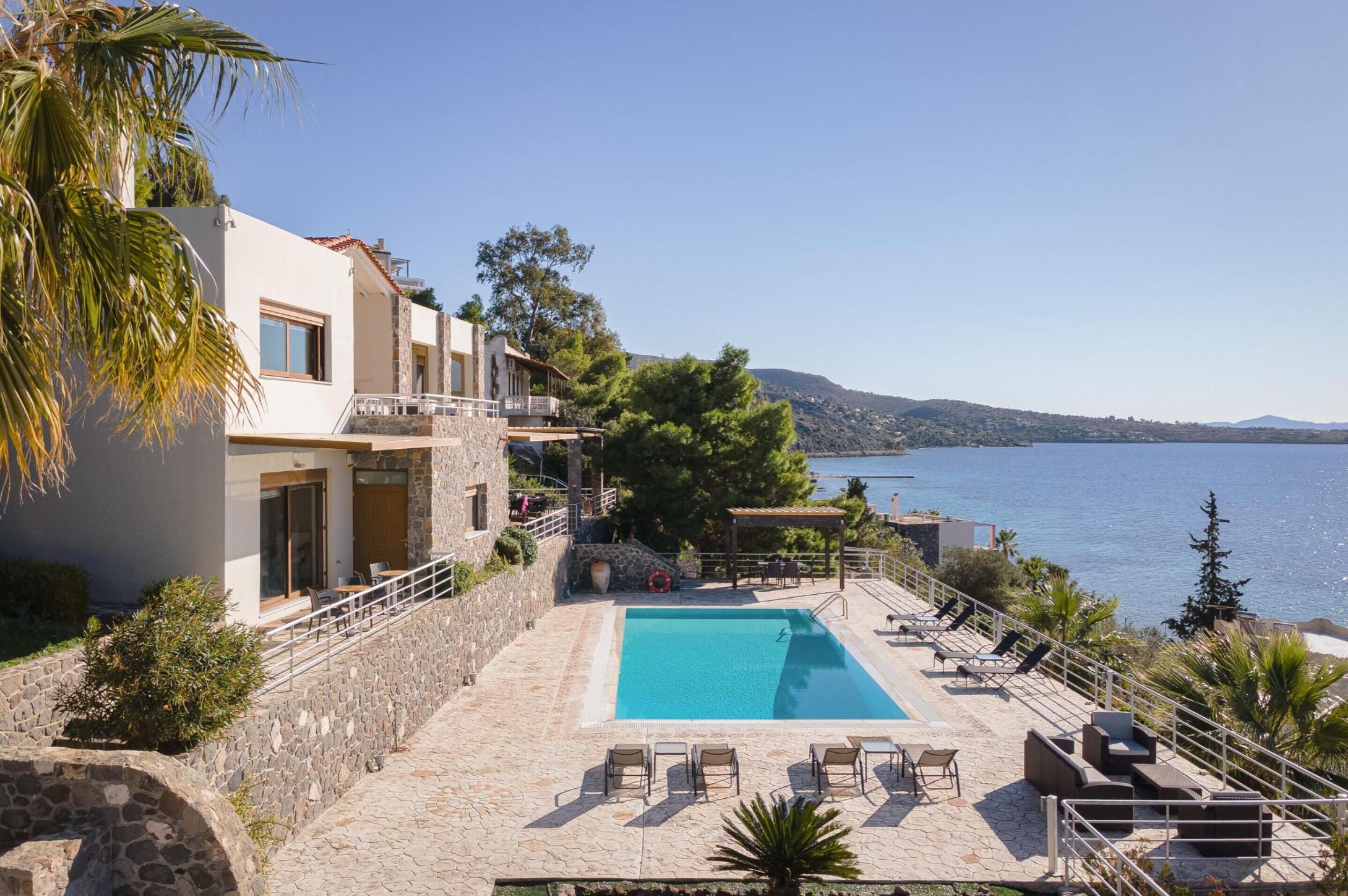A modern building with a swimming pool and outdoor seating, overlooking a body of water.