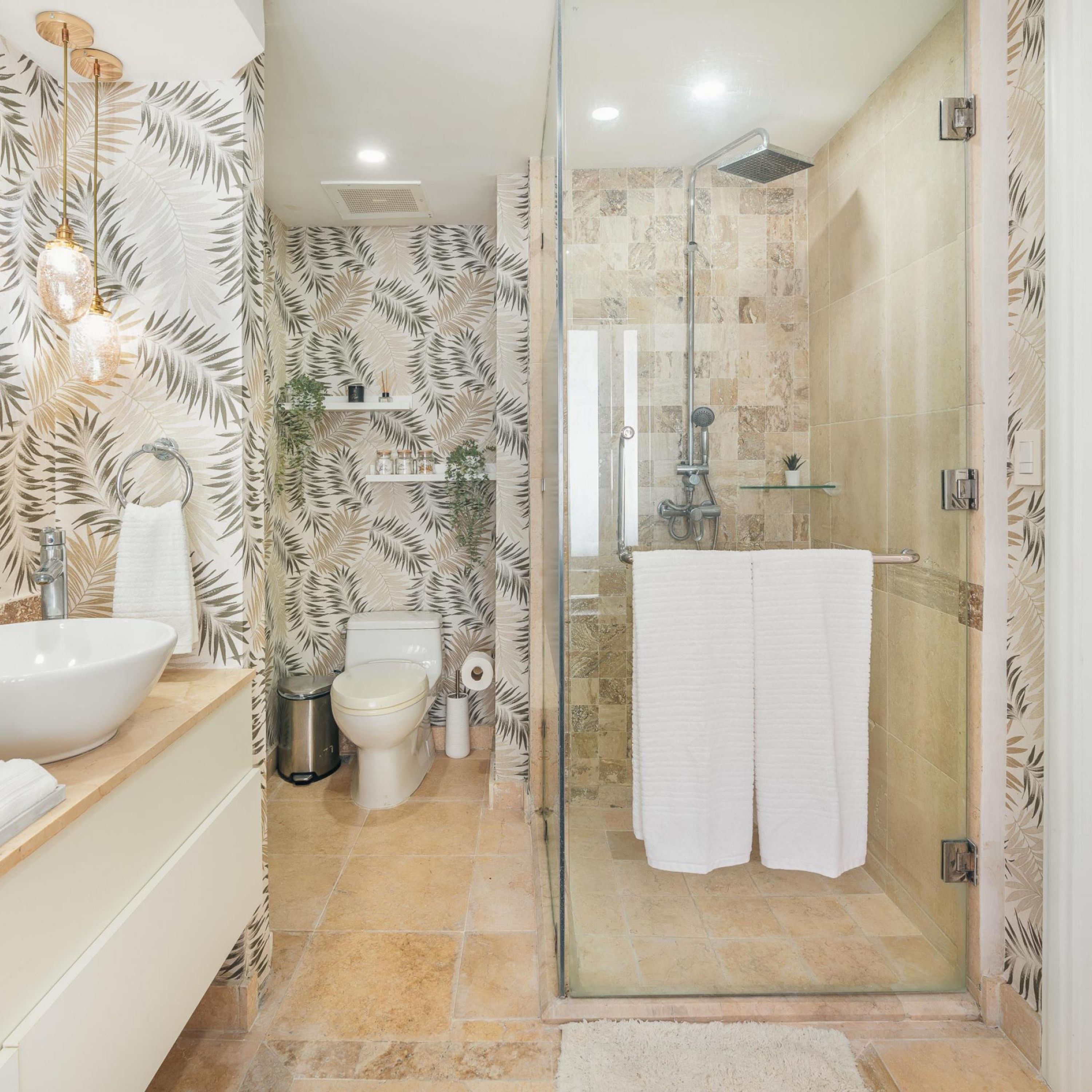 A modern bathroom with a glass shower enclosure, a white sink, and a toilet.