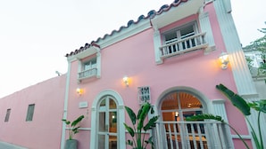A pink building with white trim, large potted plants, and a balcony with a railing. - Hotel Sublime (Cartagena)