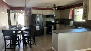 Una cocina moderna con una isla central, electrodomésticos de acero inoxidable y un comedor con una mesa redonda y sillas.