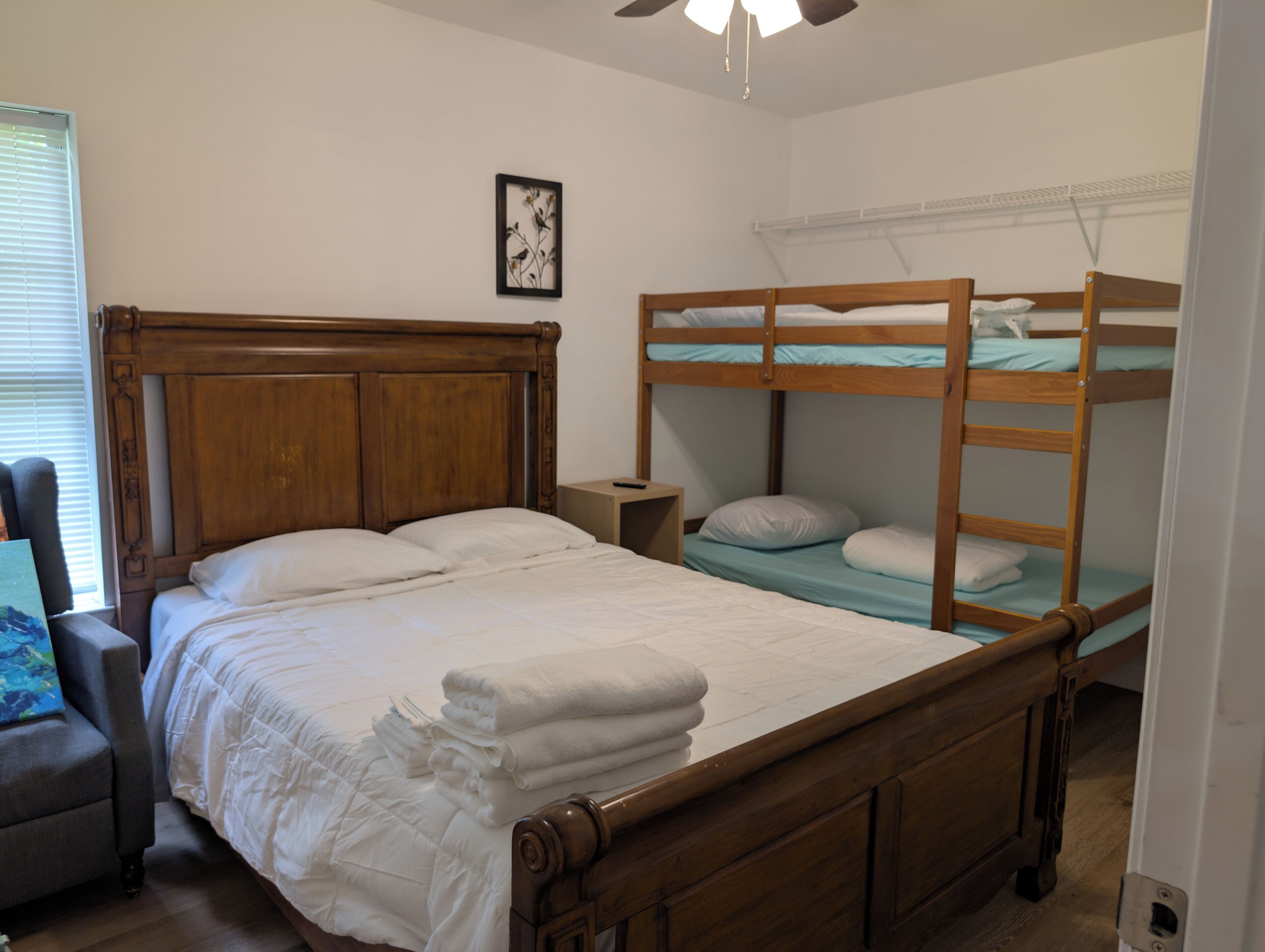 Une chambre à coucher avec un lit en bois, un lit superposé, une chaise et une table de chevet.