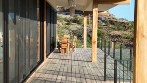 Une terrasse en bois avec une table et des chaises, offrant une vue sur un paysage montagneux.