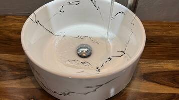 Un lavabo de cerámica blanca con líneas decorativas negras, sobre una encimera de madera.