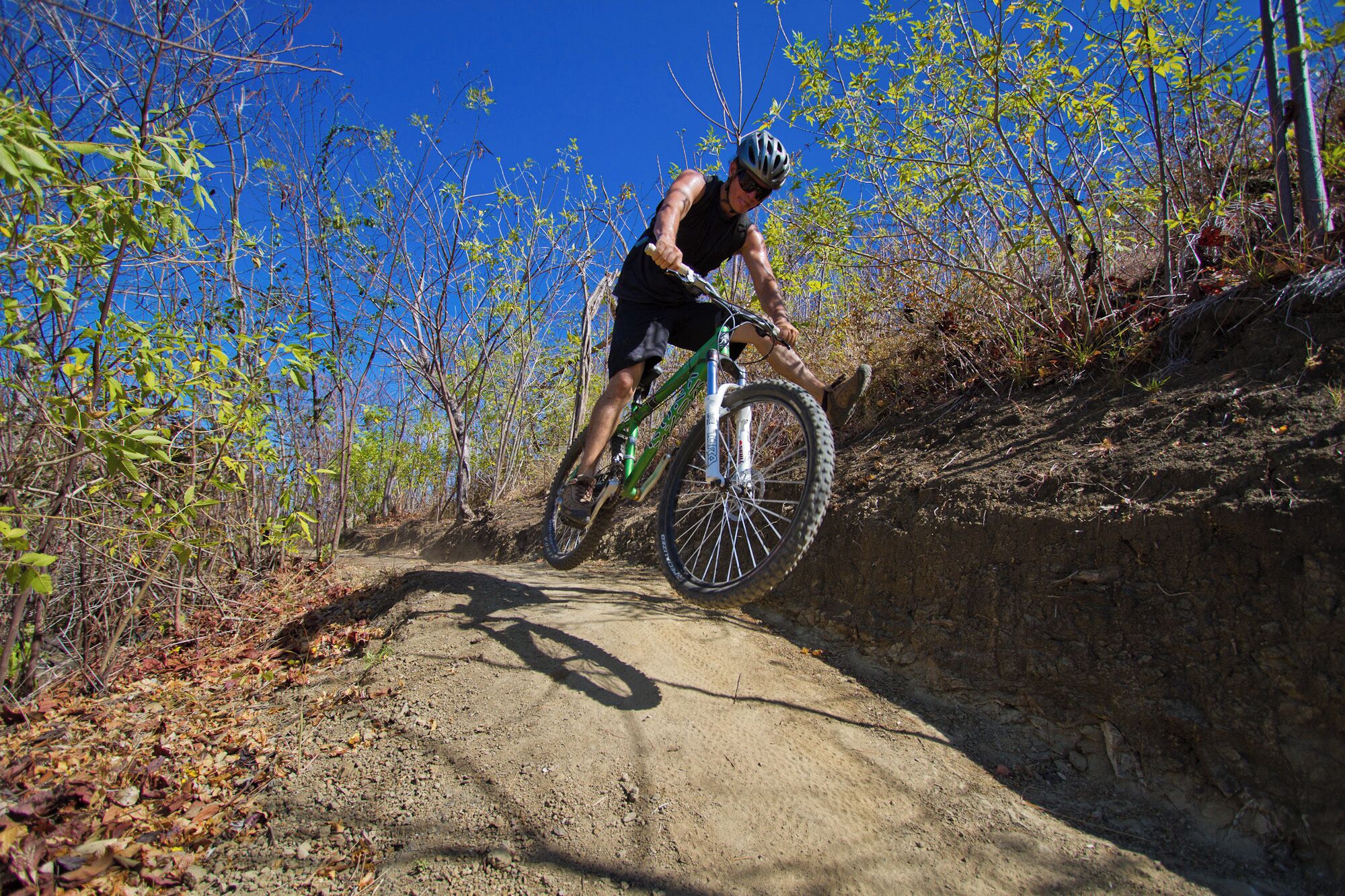 A person riding a mountain bike on a dirt trail surrounded by trees.