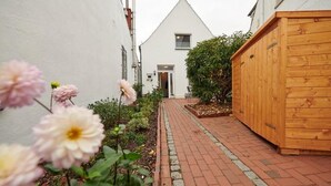 A narrow brick pathway leading to a white building with a triangular roof.