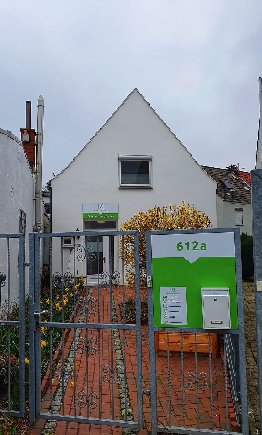 A white building with a green sign reading "Marion Weber Homes" and "Ferienwohnung Sophia" with a number "612a".