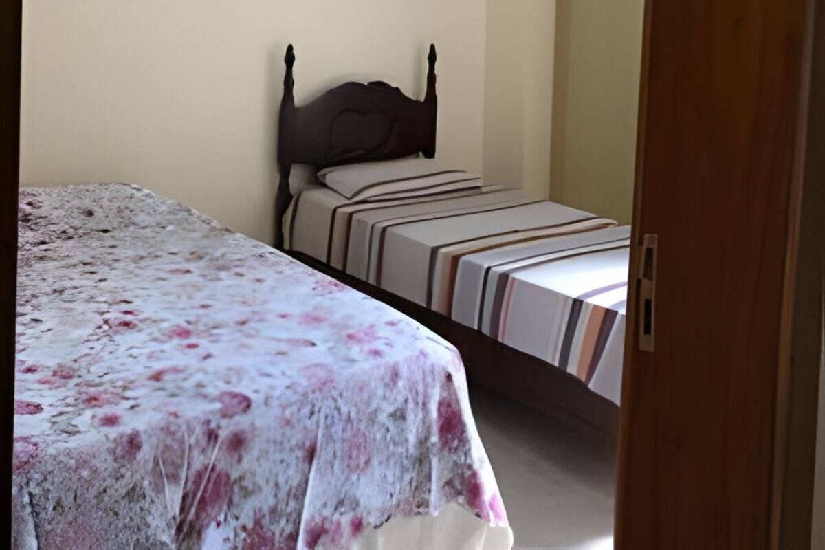 A bedroom with a bed, a ceiling fan, and a door.