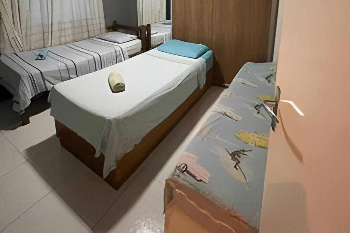 A bedroom with two single beds, a ceiling fan, a large mirror, and a wardrobe.