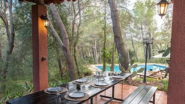 An outdoor dining area with a table set for four, overlooking a pool.