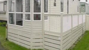 A single-story mobile home with a front porch, a satellite dish, and a large window on the front. - Luxury 2 Bed Caravan Heacham Beach Pets go Free (King's Lynn)