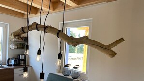 A rustic kitchen with wooden beams, hanging light bulbs, and a view of the outdoors. - Ein Urlaub in drei Ländern! Whirlpool, Sauna, Grill (Arnoldstein)