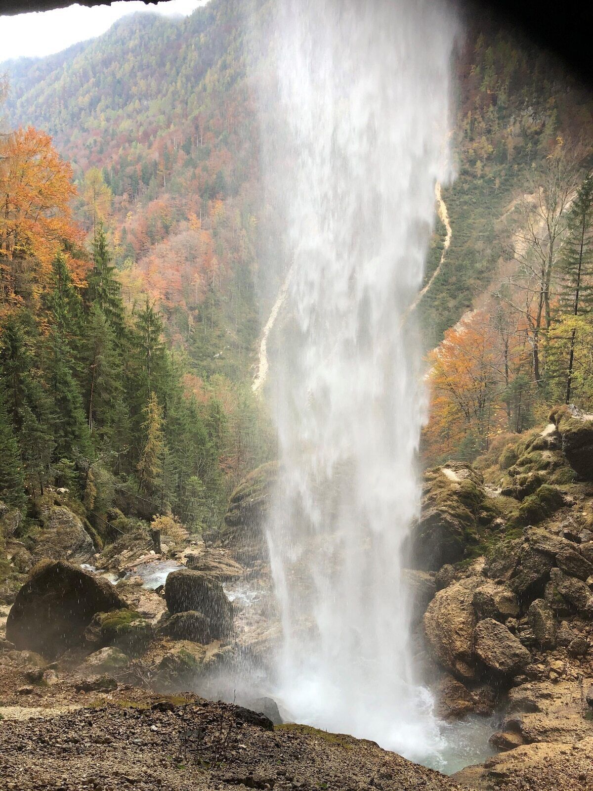 Una cascada se precipita por un acantilado rocoso, rodeada de follaje otoñal.