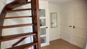 A staircase leading to a room with a white door, a mirror, and a closet with two doors.