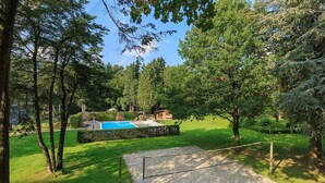 A backyard with a swimming pool, a wooden deck, and a well-maintained lawn.
