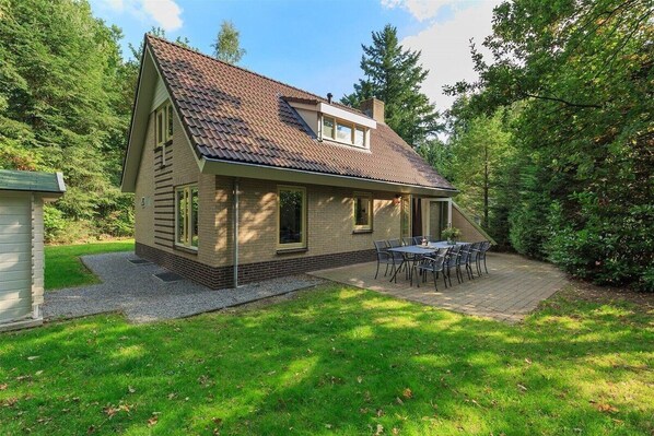 A single-story house with a sloped roof, a small attached garage, and a patio with outdoor furniture.
