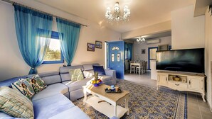 A living room with a sofa, coffee table, and TV. There is a dining area with chairs and a table.