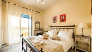 A neatly made bed with a headboard, a bedside table with a lamp, and a window with curtains.