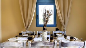 Une table à manger dressée avec des assiettes, des tasses et un vase contenant des fleurs séchées.