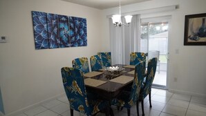 A dining area with a table and chairs, a chandelier, and a large abstract painting on the wall.