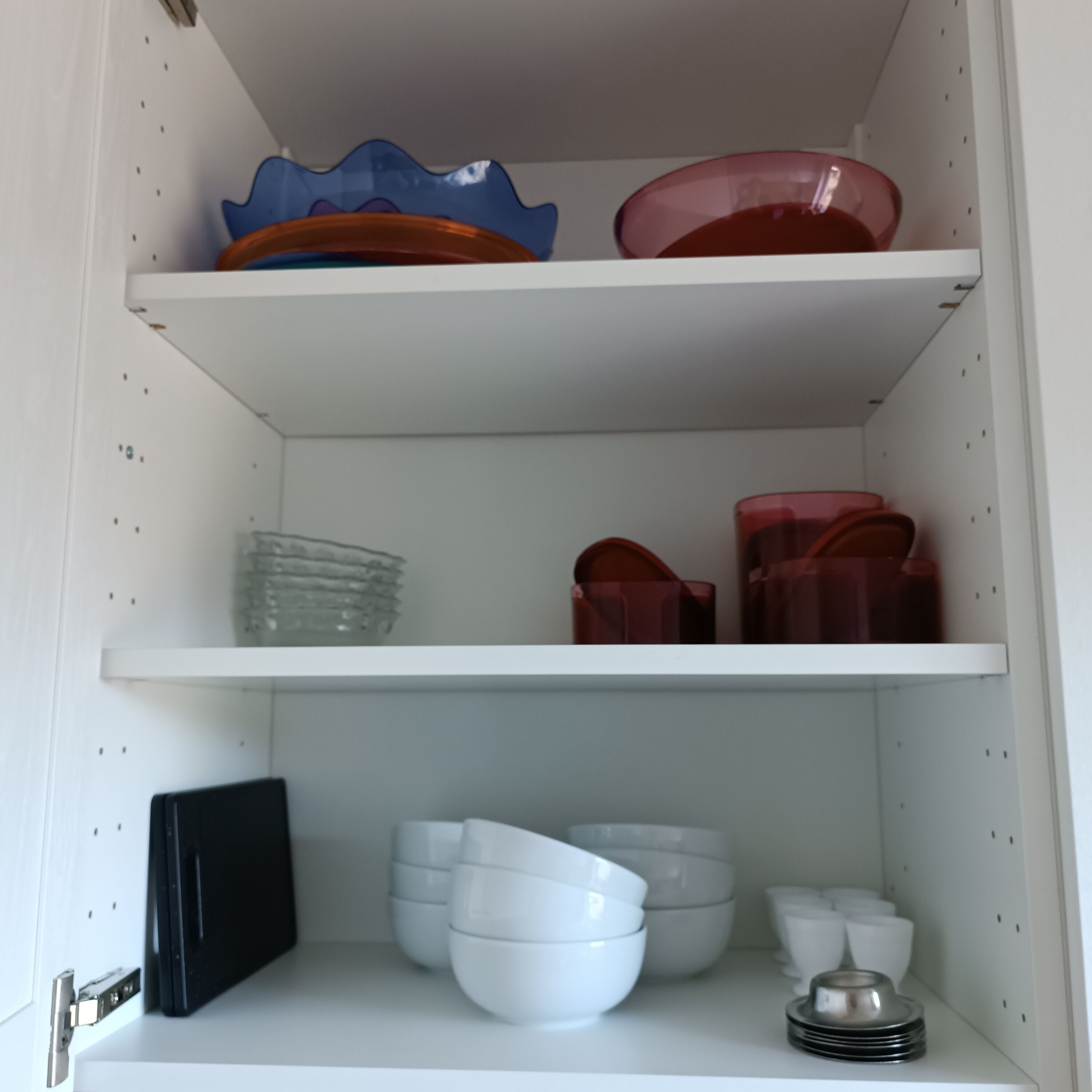 A kitchen with white cabinets, a black appliance, and various dishes and bowls.