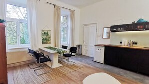 A modern kitchen with a dining area, a window with curtains, and a view of greenery outside. - Yellow Palm - 60m2 - cozy, central with a green view (Wien)