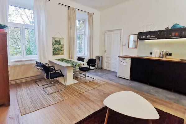 Een moderne keuken met een eethoek, een raam met gordijnen en uitzicht op groen.